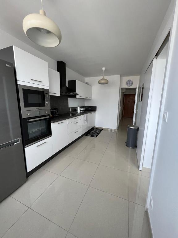 a kitchen with white appliances and white tile floors at Super 4 Pièces refait à neuf in Villeurbanne