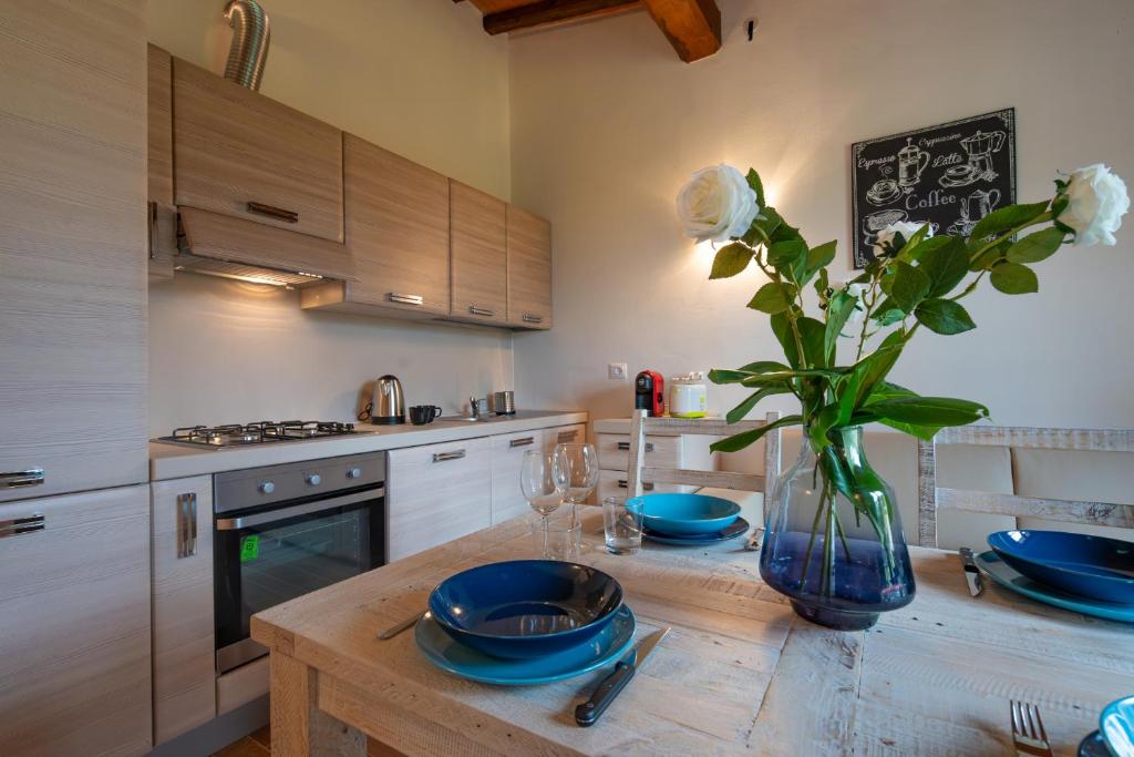 a kitchen with a table with plates and a vase of flowers at Casa d'Orcia in Pienza