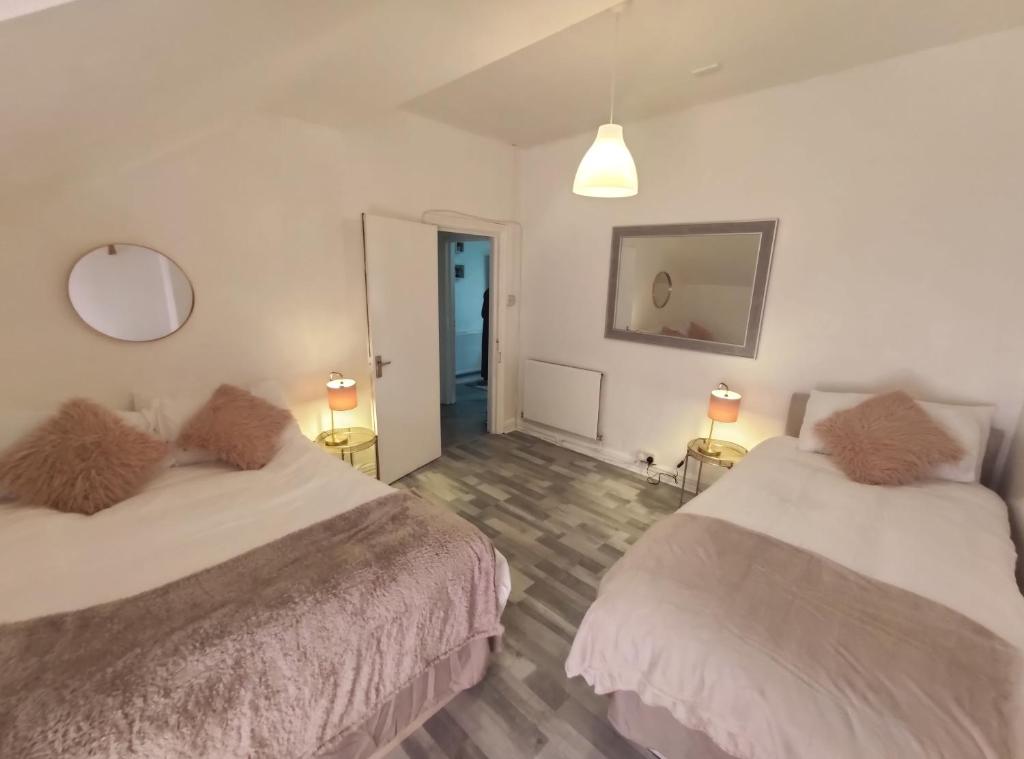 a bedroom with two beds and two lamps and a mirror at 1 Bedroom Flat w/ 2 beds in Cardiff