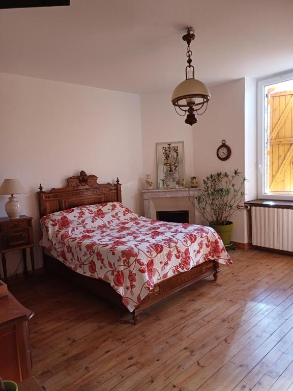 a bedroom with a bed with a red and white blanket at E lu chantauziau in La Monnerie-le Montel