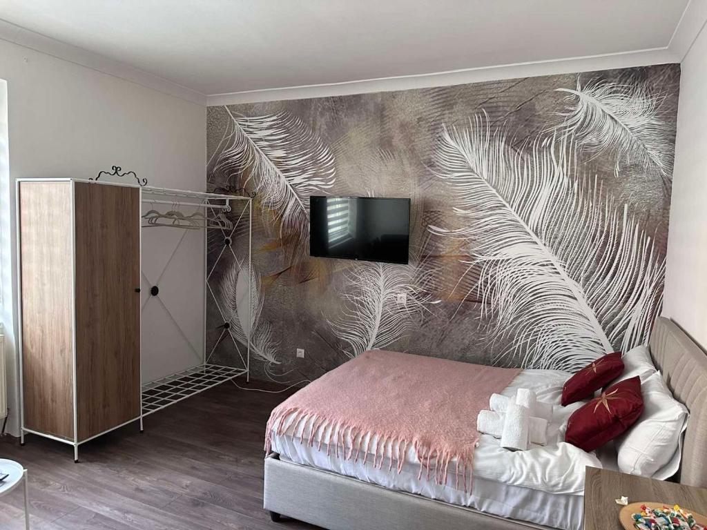 ein Schlafzimmer mit einer Wand mit einem Wandbild von Federn in der Unterkunft Royal Bistrik Apartment in Sarajevo