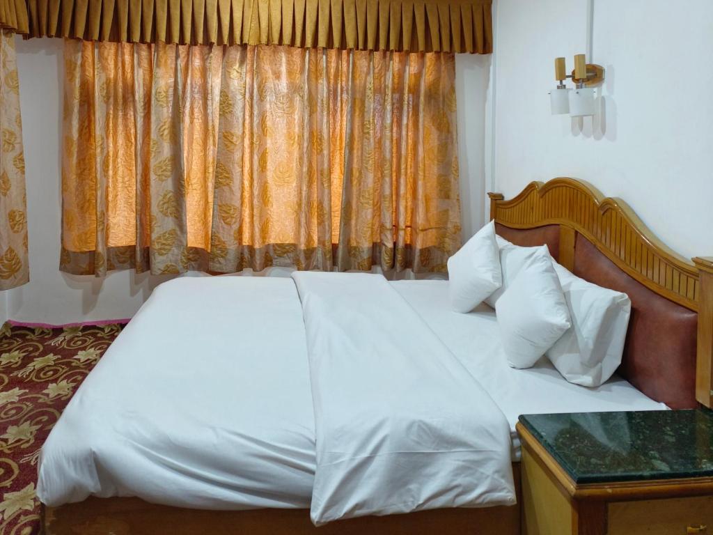 a bedroom with a large white bed and a window at Royal galaxy in Pahalgām