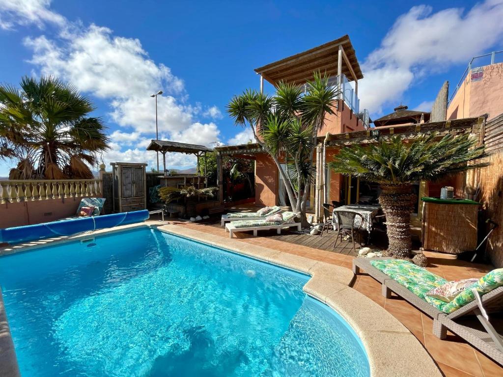 una piscina en un patio trasero con palmeras en Casa Zen Caleta de Fuste, en Caleta de Fuste