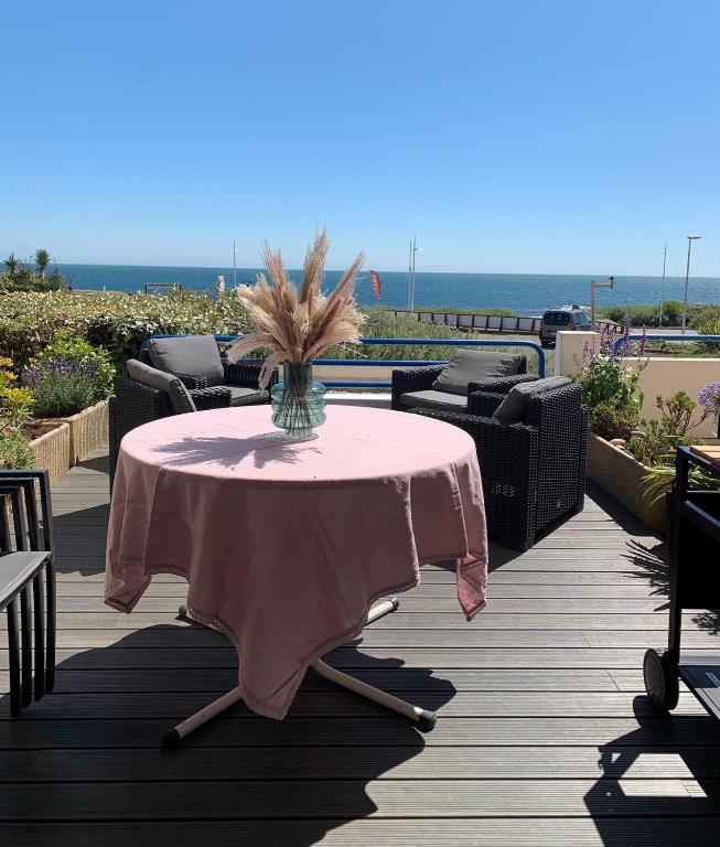 une table rose avec un vase de fleurs sur une terrasse dans l'établissement Appartement rénové dans résidence de vacances proche océan Les Sables, à Les Sables-dʼOlonne