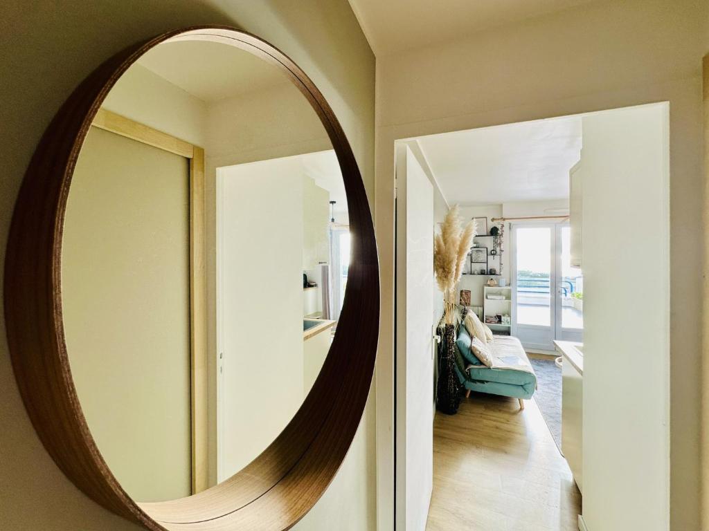 a large round mirror on the wall of a living room at Appartement rénové dans résidence de vacances proche océan Les Sables in Les Sables-dʼOlonne
