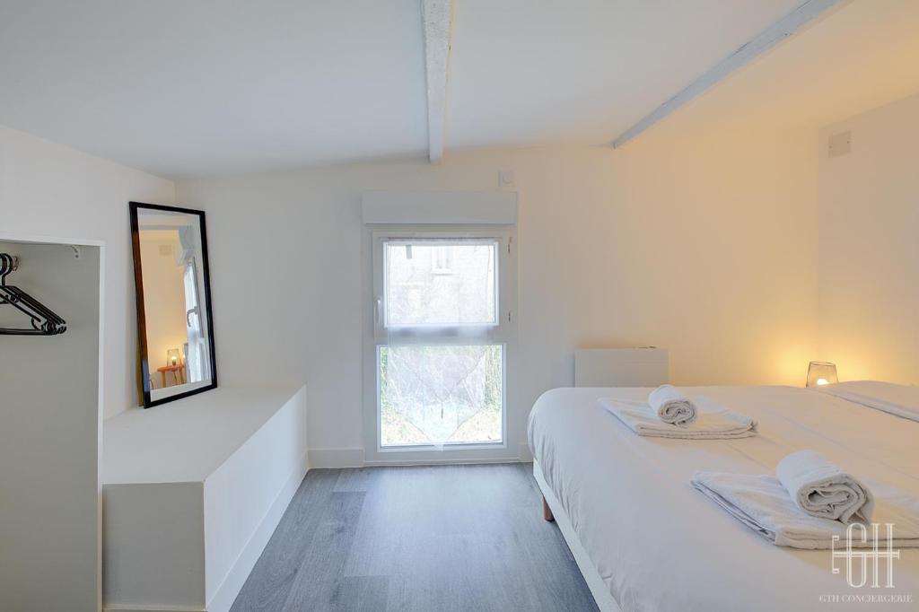 a white bedroom with a bed and a window at HALTE 3 &#47; GUÈS DE VEIGNE in Veigné