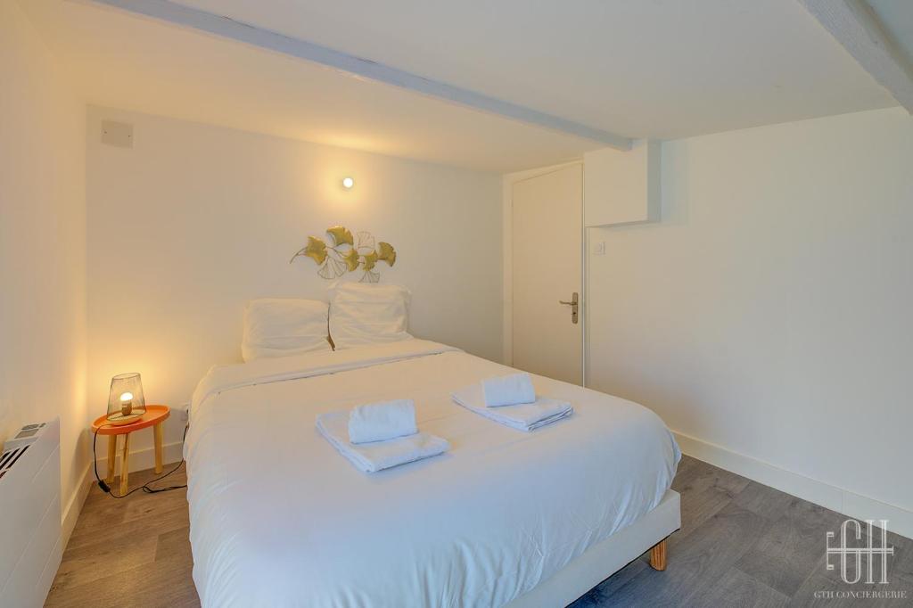 a bedroom with a white bed with two towels on it at HALTE 3 &#47; GUÈS DE VEIGNE in Veigné