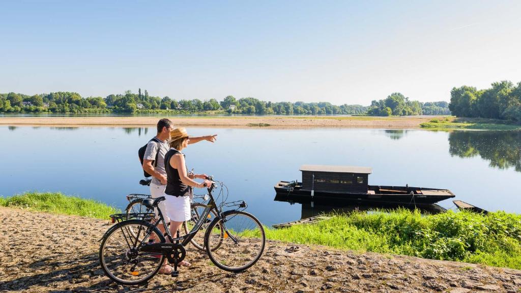 a man and a woman standing next to a bike next to a lake at HALTE 3 &#47; GUÈS DE VEIGNE in Veigné