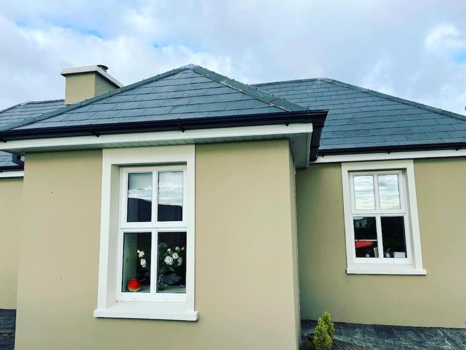 una casa con due finestre e un tetto nero di Mountain View - Cosy Country Cottage a Cahersiveen