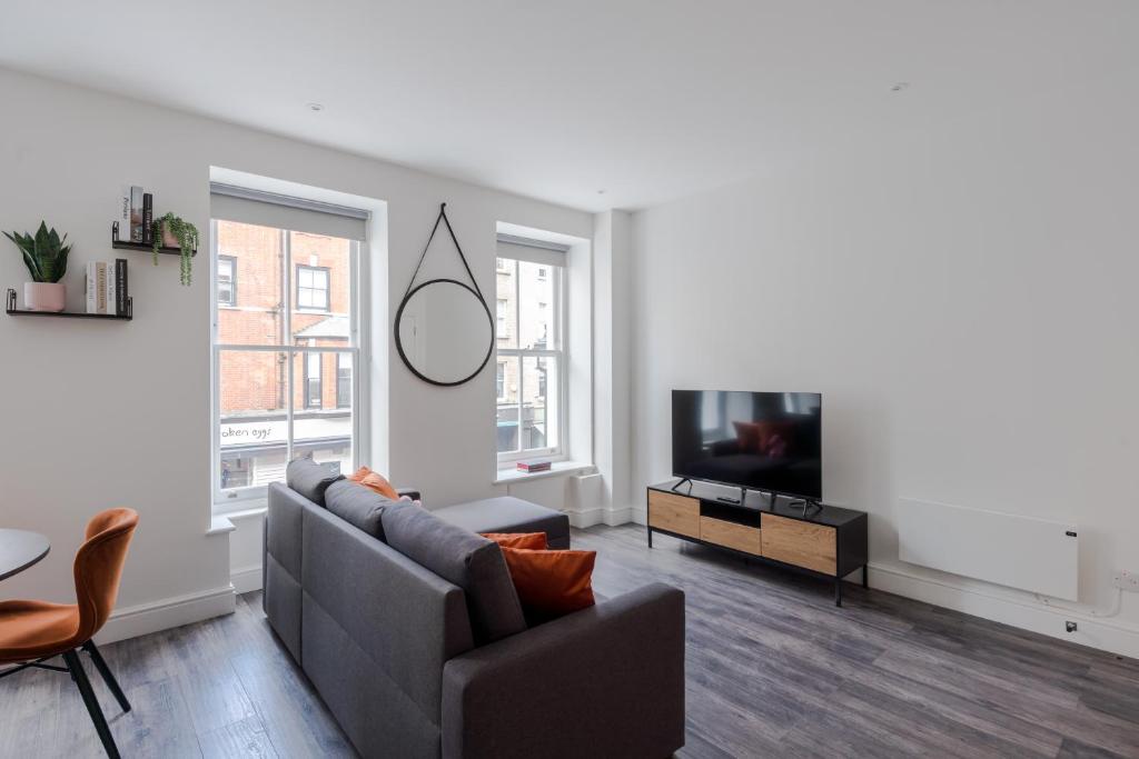 a living room with a couch and a tv at Frankie Says- Cosy up in the Fitz and Flirty, a swish, modern 1 BR apartment in the heart of the West End in London