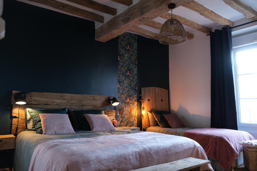 two beds in a room with black walls at Gite Le Cozy in Val-au-Perche