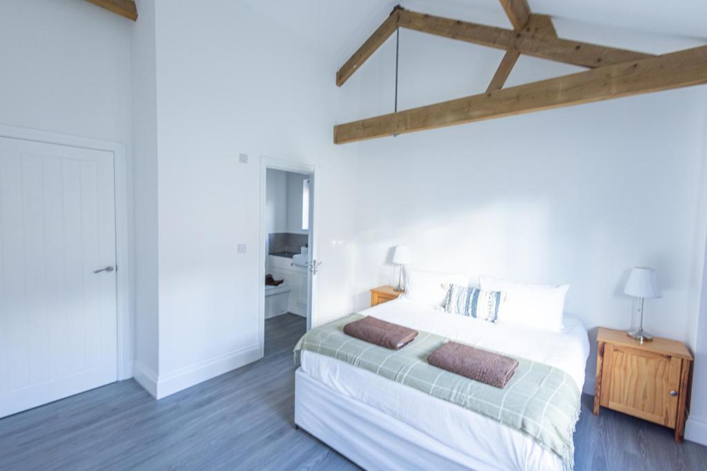 a bedroom with a white bed and a wooden ceiling at Hedgehogs Home at Tove Valley Cottages in Towcester