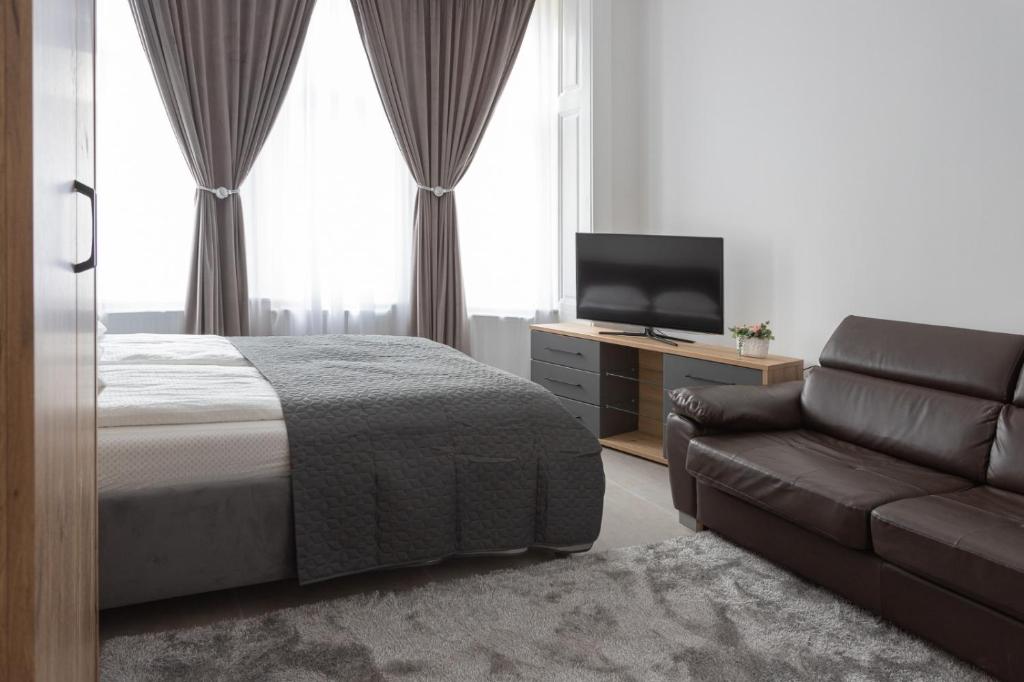 a bedroom with a bed and a couch and a television at AVA City Center SATU MARE in Satu Mare