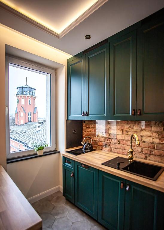 a kitchen with green cabinets and a window at Apartament „Nad Ratuszem” in Częstochowa