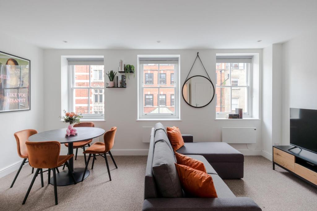 ein Wohnzimmer mit einem Sofa und einem Tisch in der Unterkunft Frankie Says - Stylish, spacious and centrally located near Oxford Circus, say hello to the gorgeous Goodge Vibes Only 1 BR apartment in London