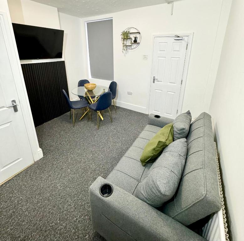 a living room with a gray couch and a table at NEW Unique 4 Bed Families Contractors 靠近唐人街 in Nottingham