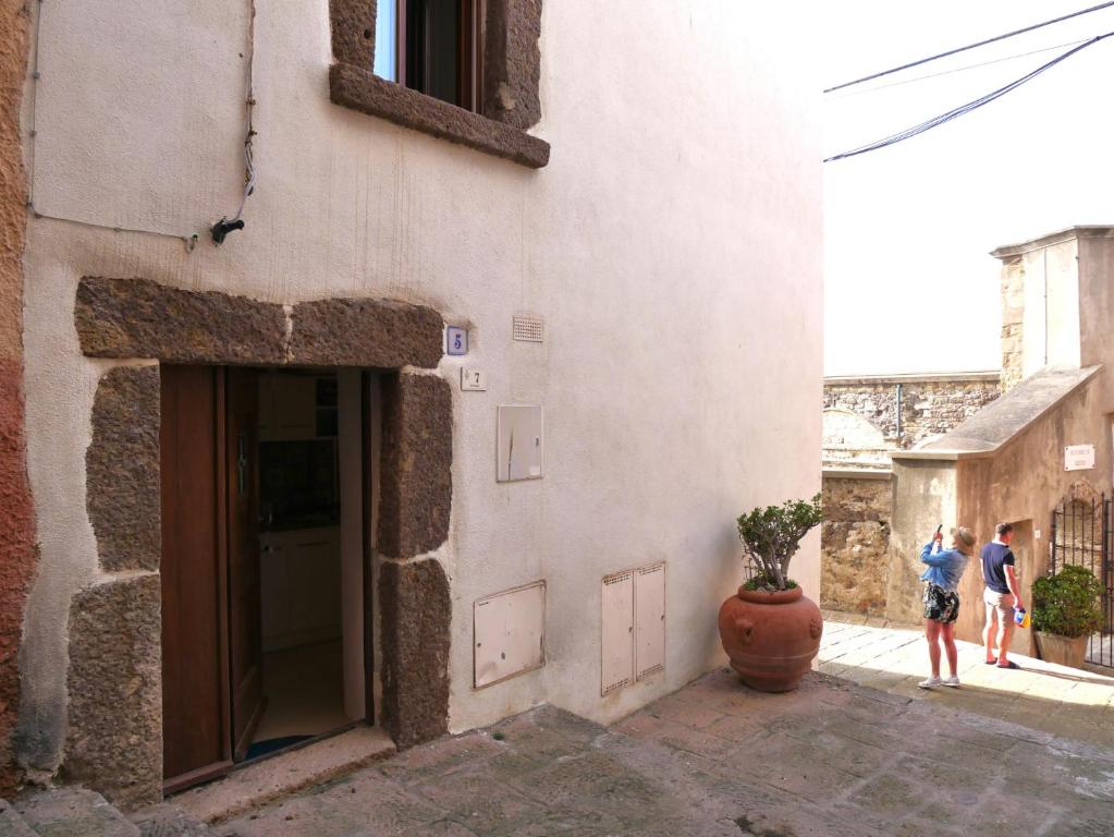 twee mensen staan buiten een gebouw met een vaas bij Suite della Contessa in Castelsardo