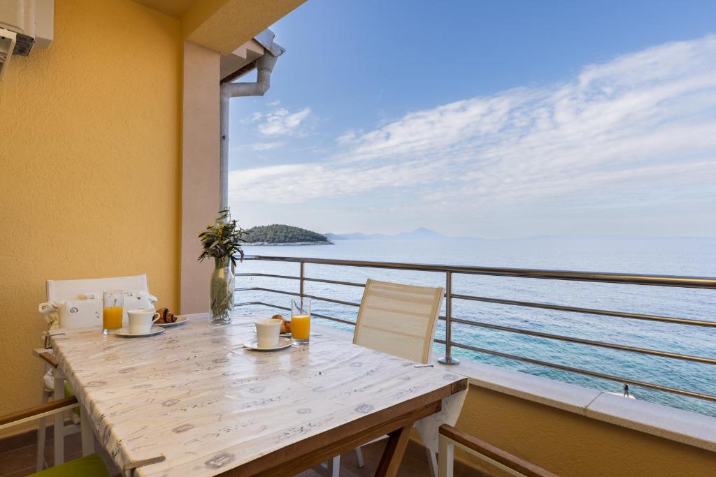 a balcony with a table with a view of the ocean at BELLAVISTA apartman Punta in Veli Lošinj
