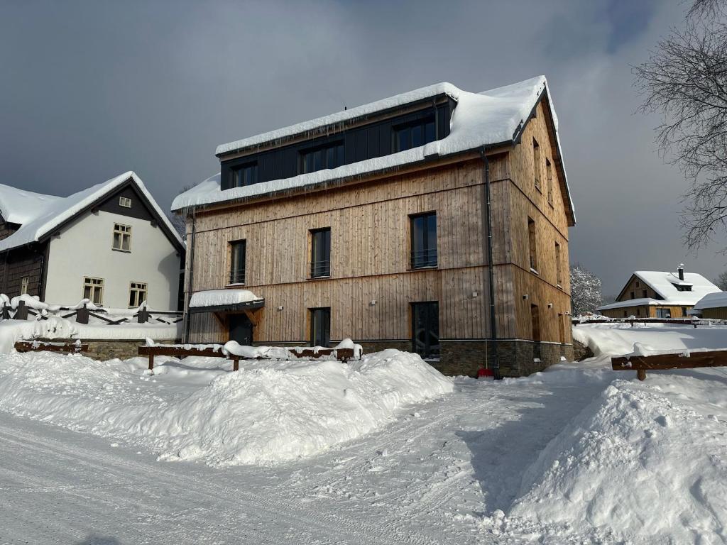 a large wooden building with snow on the ground at Helly - Kvilda - apartmány in Kvilda