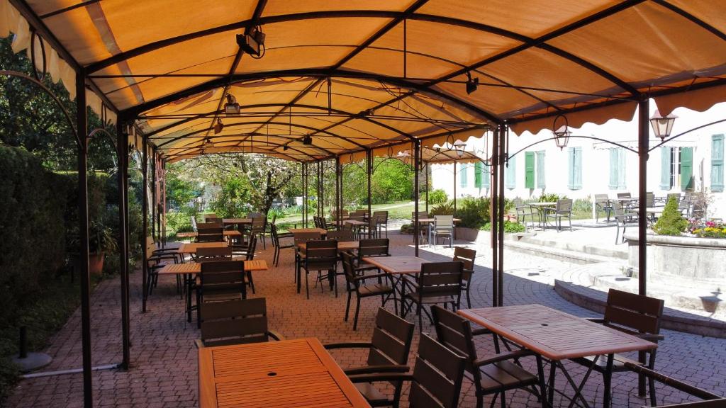 a restaurant with wooden tables and chairs under a tent at Hotel Carmel in Les Vans