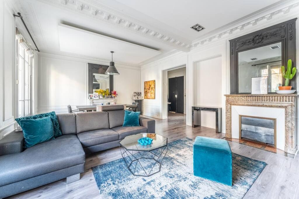 een woonkamer met een bank en een open haard bij luxueux appartement haussmannien in Saint-Mandé