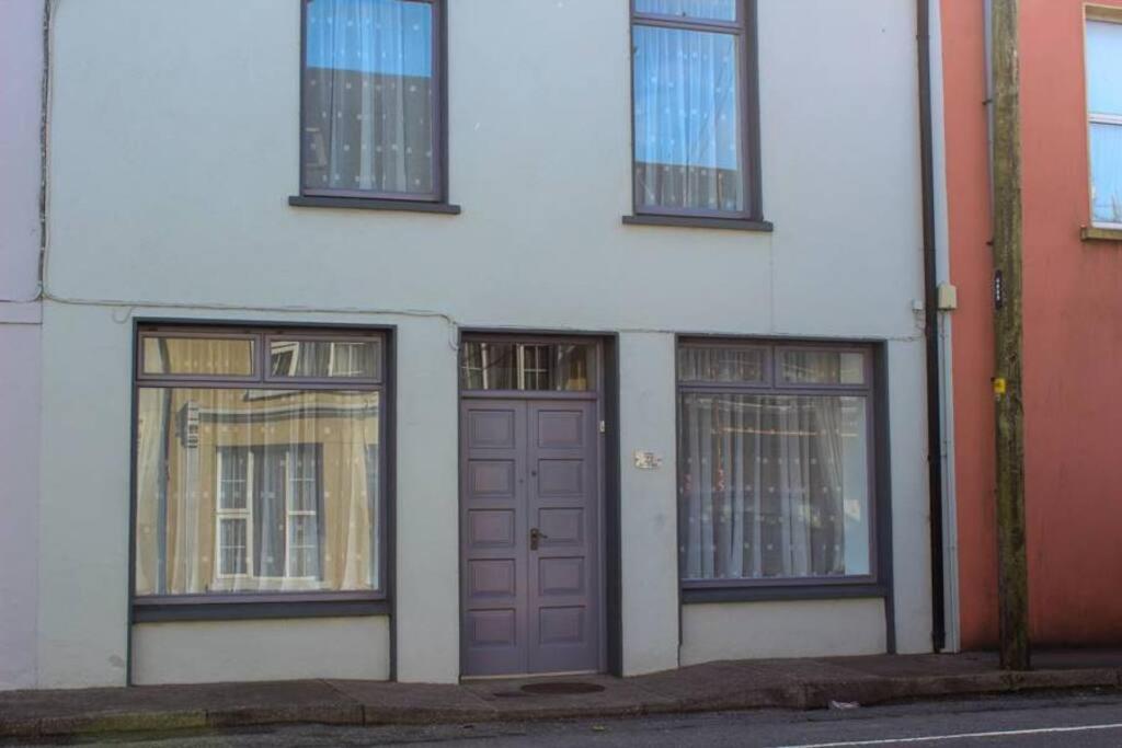 un edificio blanco con puertas y ventanas moradas en Katie's Town House, en Cahersiveen