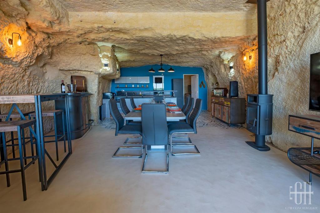 a dining room in a cave with a table and chairs at La Troglo - Maison typique de notre région in Vouvray