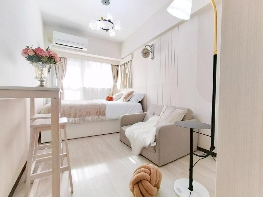 um pequeno quarto branco com uma cama e um sofá em Z81新宿最中心 東新宿站5分 2室-Shinjuku center 5 mins to Station, Max 6P 直达新宿 涉谷 表参道 池袋 上野 代代木 银座 原宿 em Tóquio