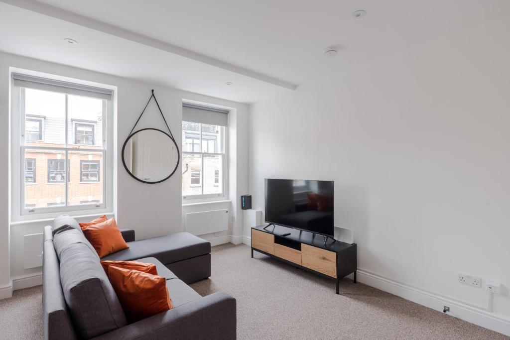 sala de estar con sofá y TV de pantalla plana en Frankie Says - London lodgings don't get more fabulous than the Fitz n' Glamour, a dazzling 1 BR apartment in central Fitzrovia, en Londres