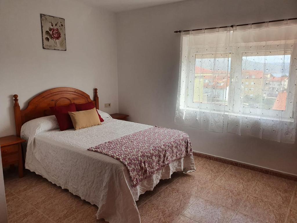 a bedroom with a bed and a window at Piso da Charca in Fisterra