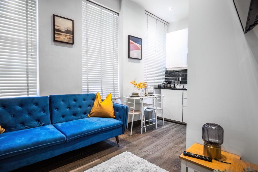um sofá azul numa sala de estar com uma cozinha em Livestay-Charming London Retreat Stylish 1BR near Kings Cross&Farrington em Londres