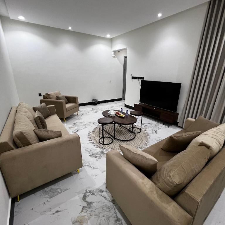 un soggiorno con divani e TV a schermo piatto di شقة فاخرة بغرفة نوم وصالة 10 Luxury APT a Riyad