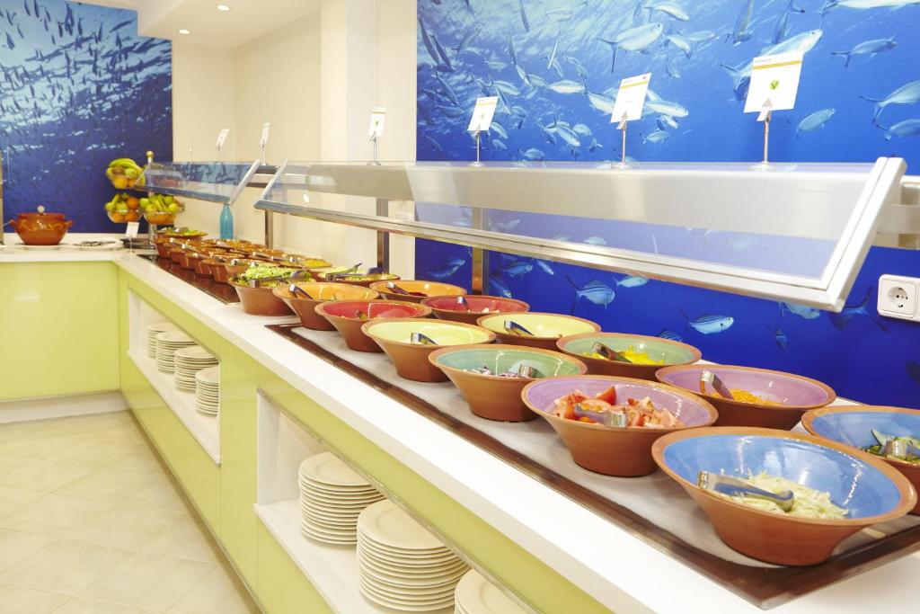 a buffet line with bowls of food in a restaurant at Universal Hotel Marqués in Colònia de Sant Jordi