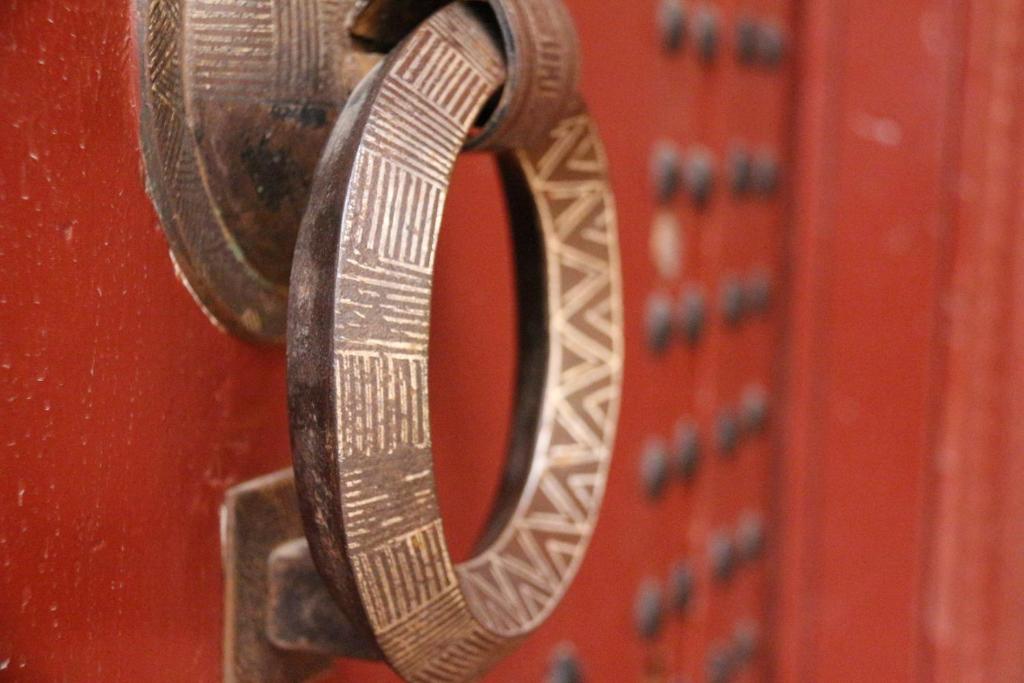 un numero metallico è appeso a una porta rossa di Riad Yamcha a Meknès