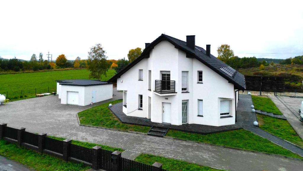 a white house in a field with a fence at Noclegi Pniów 51 