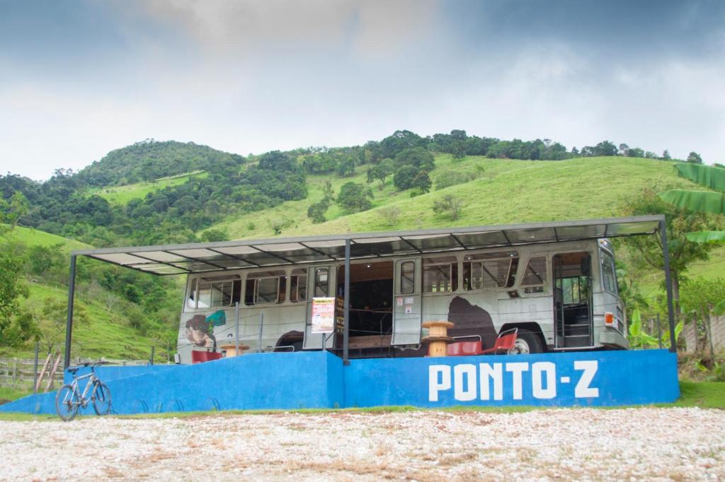 a bus stop with a roof on a hill at Chalé Bus Ponto Z in São Bento do Sapucaí