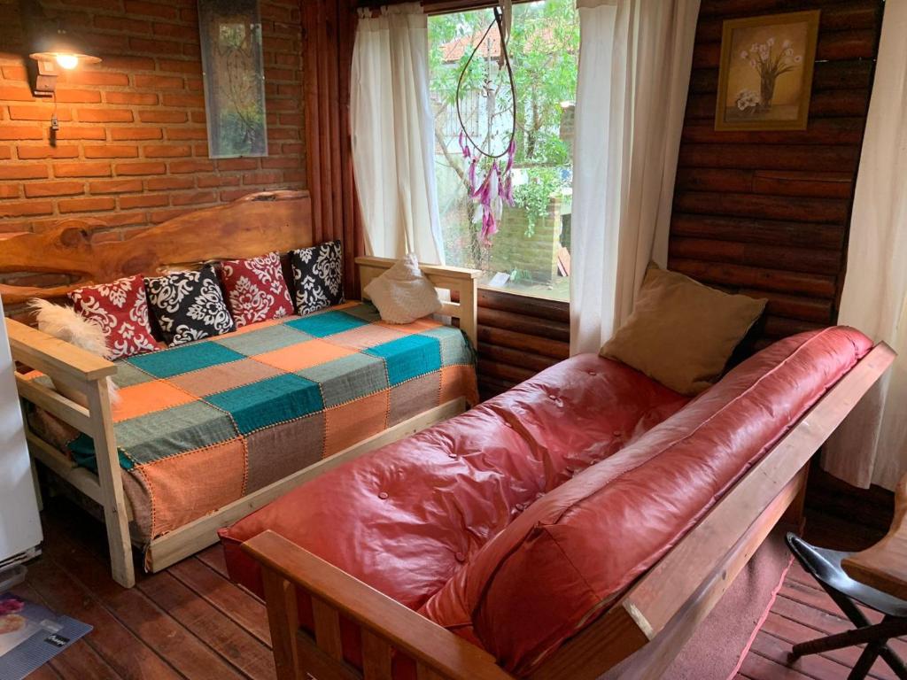 a living room with a couch and a bed and a window at Cabaña Lemu Unku, El Pinar -6 personas- in La Lucila del Mar