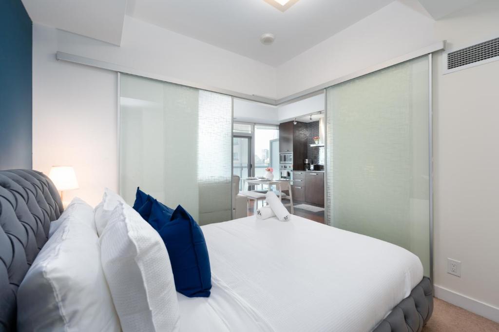 a bedroom with a white bed with blue pillows at Downtown Apartments 12 in Toronto