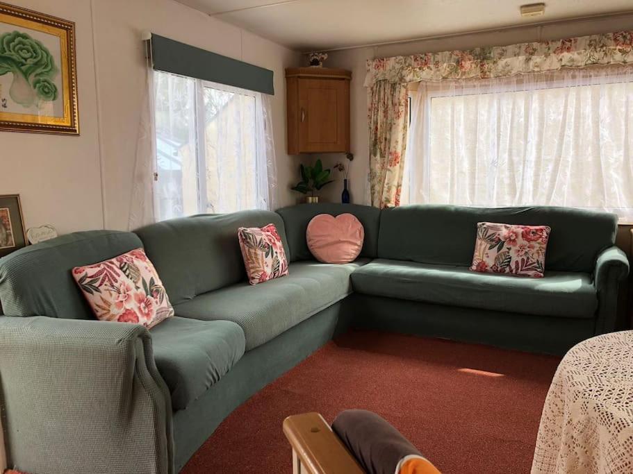 a living room with a green couch with pillows at 2 bedroom static caravan in Muirkirk