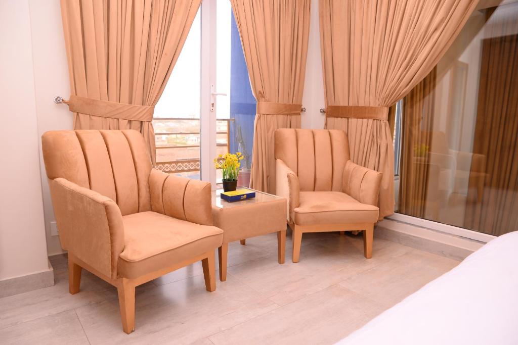 2 sillas y una mesa en una habitación con ventana en Tom's Luxury, en Peshawar