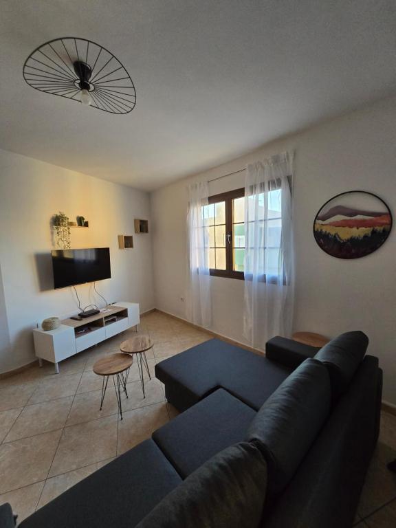 een woonkamer met een blauwe bank en een tv bij Casa Maday in Cotillo