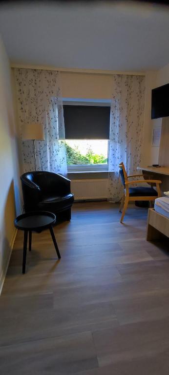 een woonkamer met een zwarte stoel en een raam bij Hotel Aits garni in Nordenham