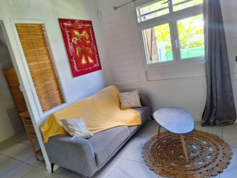 een woonkamer met een bank en een tafel bij L'EdenKrys 2 avec son jacuzzi in La Trinité