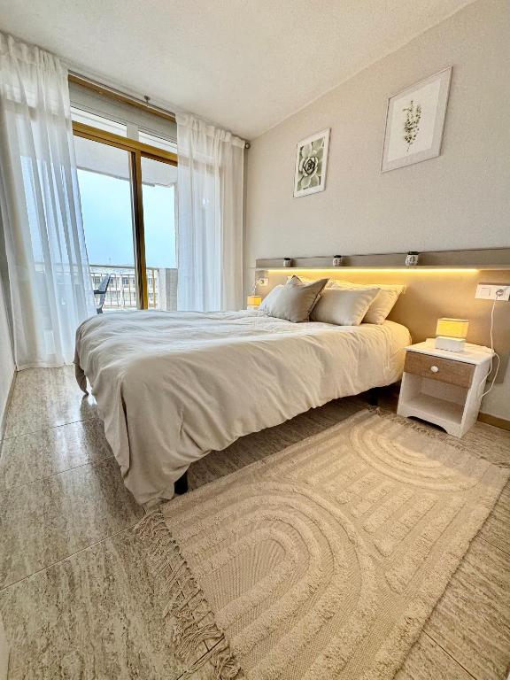 a bedroom with a large bed and a large window at Apartamento completo junto a la playa in Salou