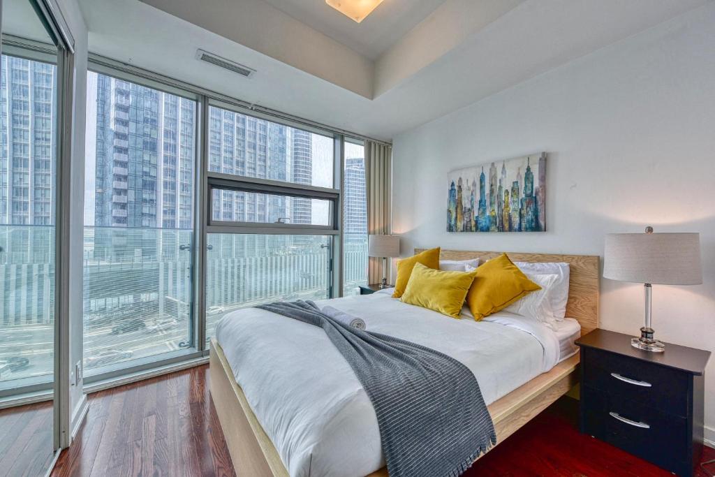 a bedroom with a large bed and large windows at Downtown Apartments 16 in Toronto