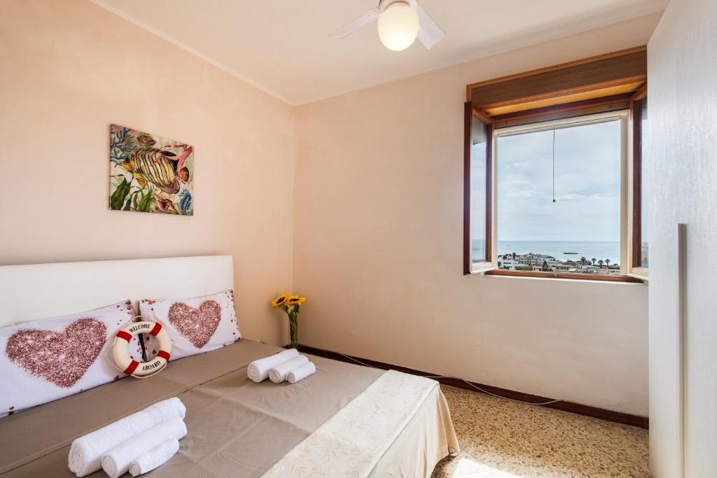 Schlafzimmer mit einem Bett und einem Fenster in der Unterkunft The Sunrise Attico Panoramico in Porto Cesareo