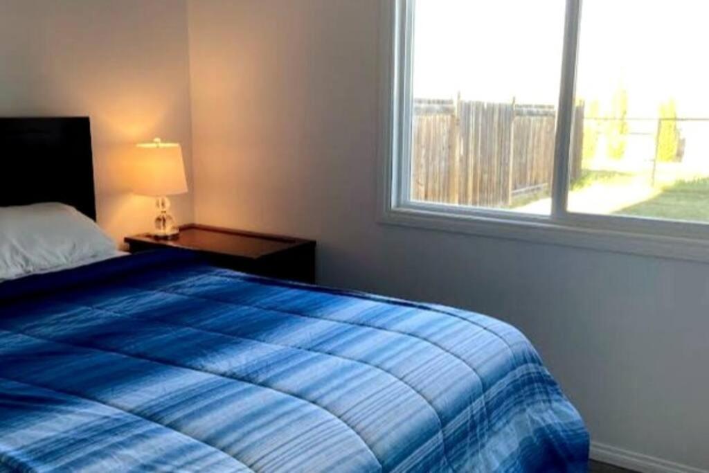 a bedroom with a blue bed and a window at Walk 2mins to Shopping & Bussing,1-Bed Room Suite in Fort McMurray