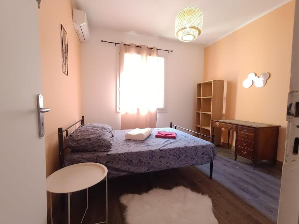 een slaapkamer met een bed, een bureau en een raam bij La Bugeotte :p in Marseille