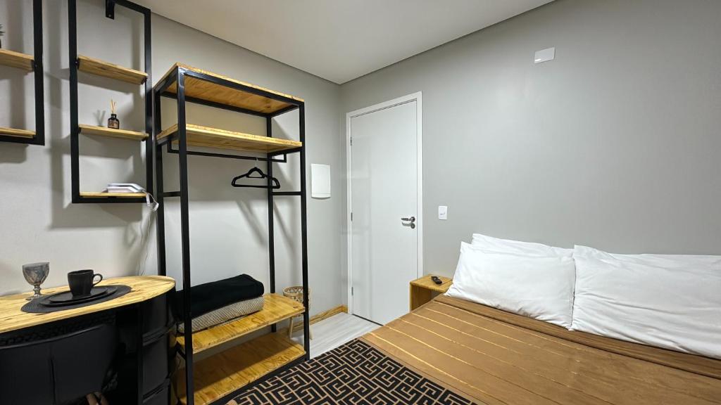 a bedroom with a bed and a desk and a shelf at 21- Studio com decoração linda in Curitiba