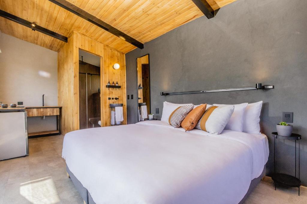 een slaapkamer met een groot wit bed met kussens bij Fuga Neusa in Tausa Viejo